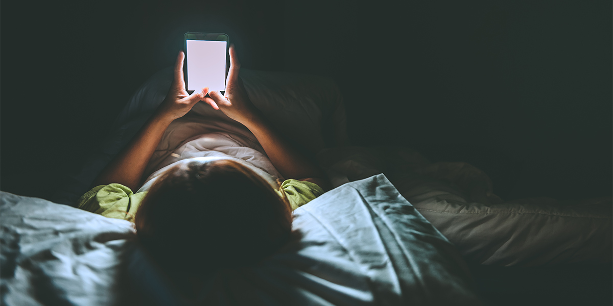Person looking at mobile device in bed