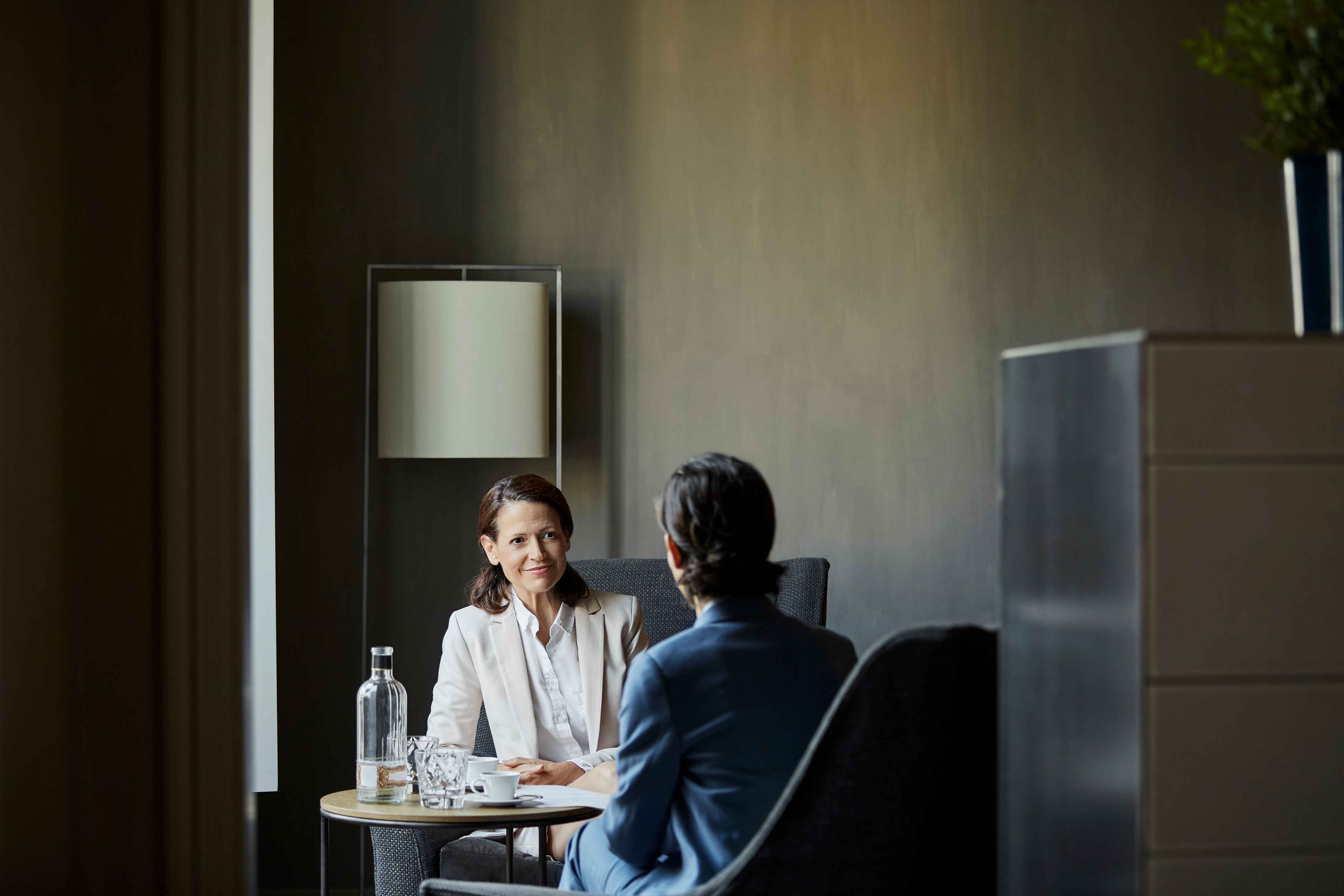 An accountant has coffee with their client in a meeting room