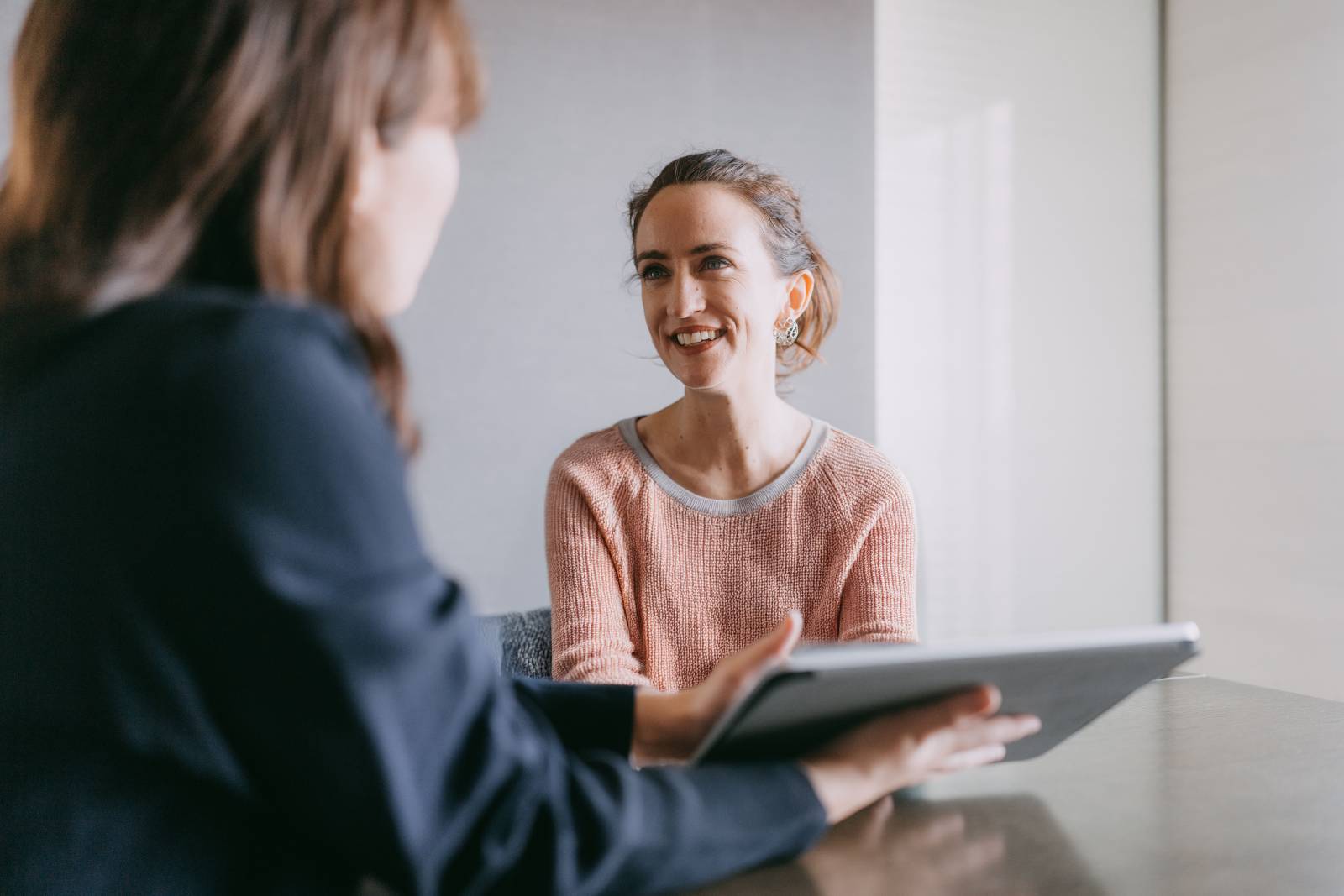 A financial adviser holds a tablet while meeting with their client