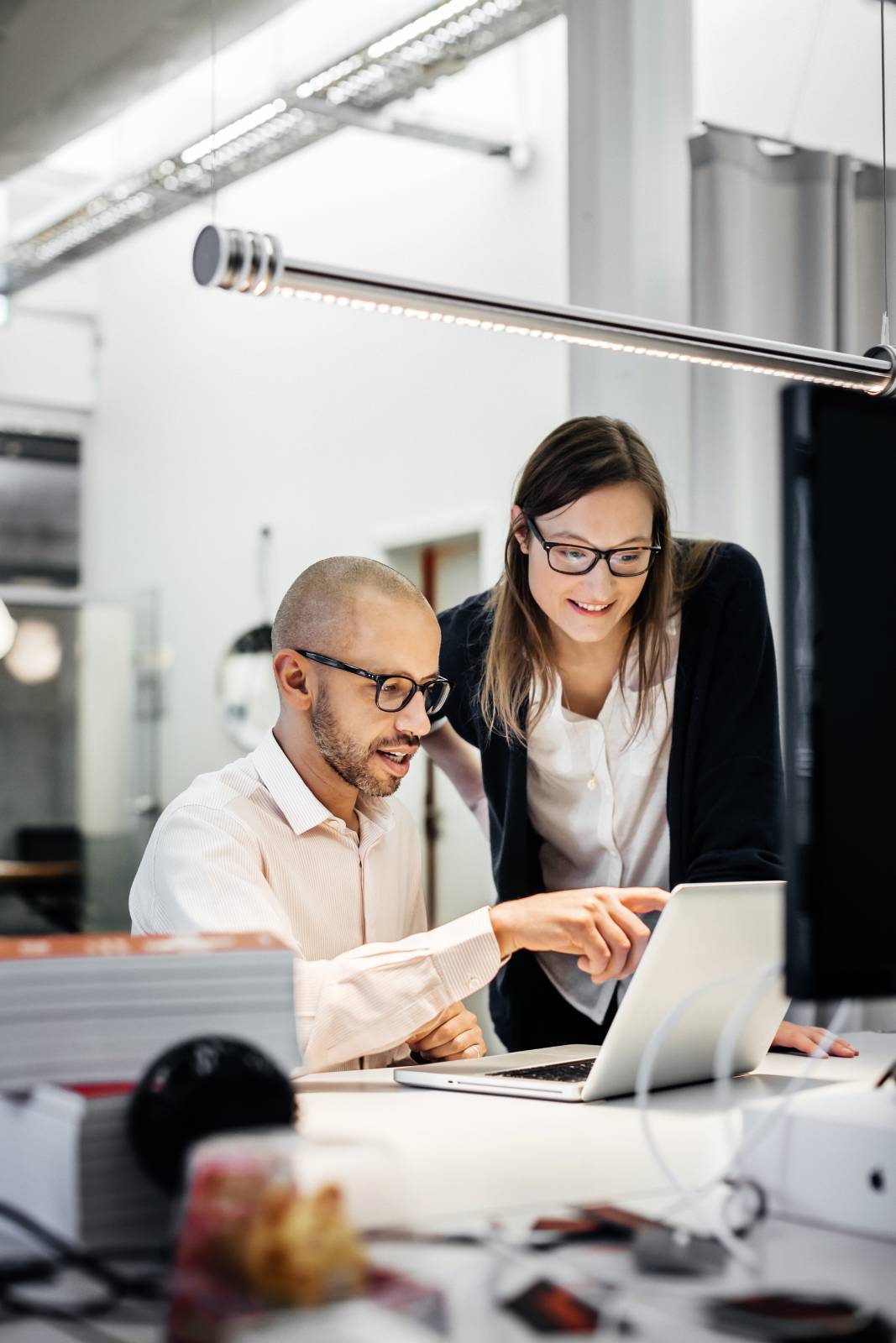 A man and woman in an office look at a laptop together