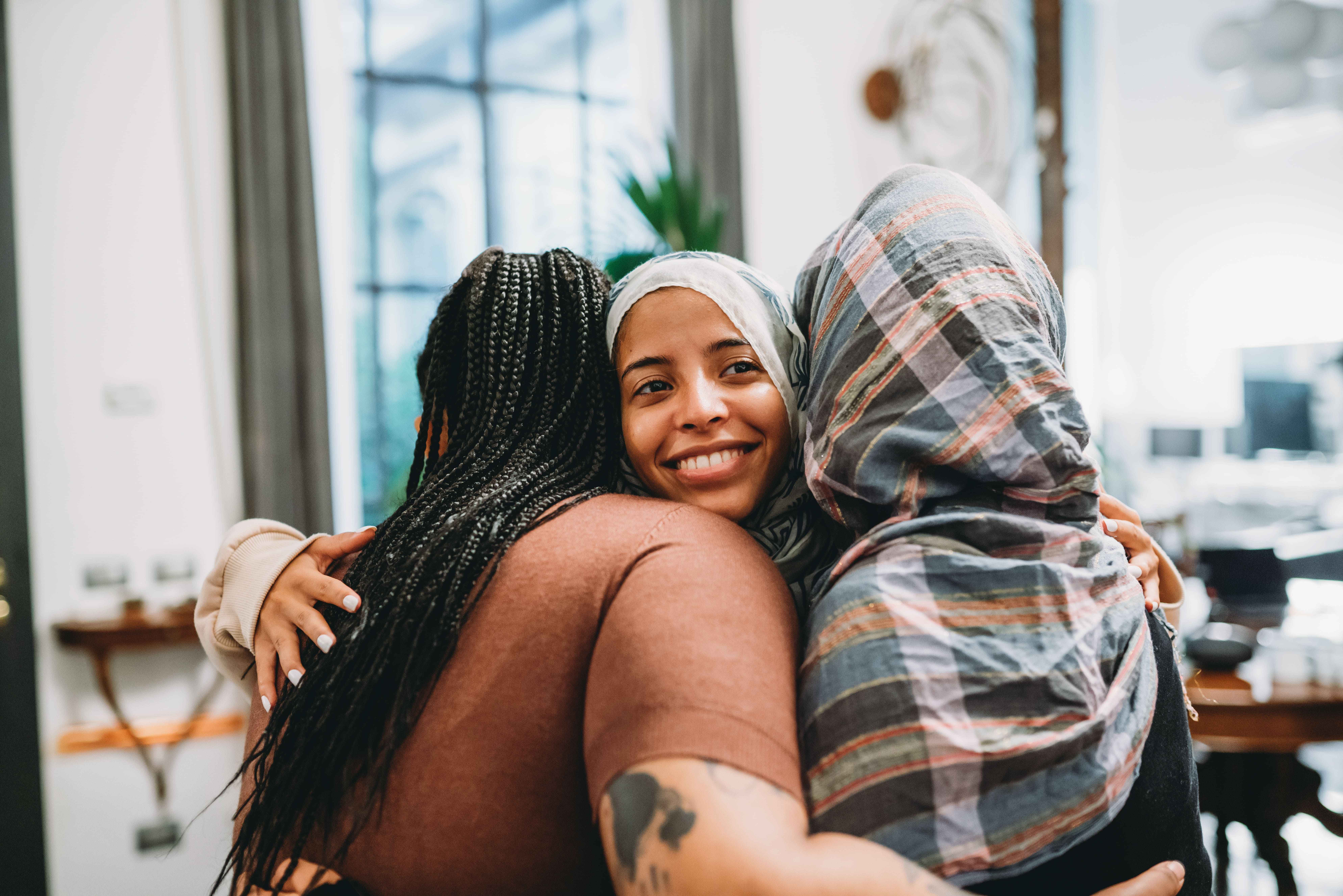 Three ladies embrace in a group hug at an event in an office
