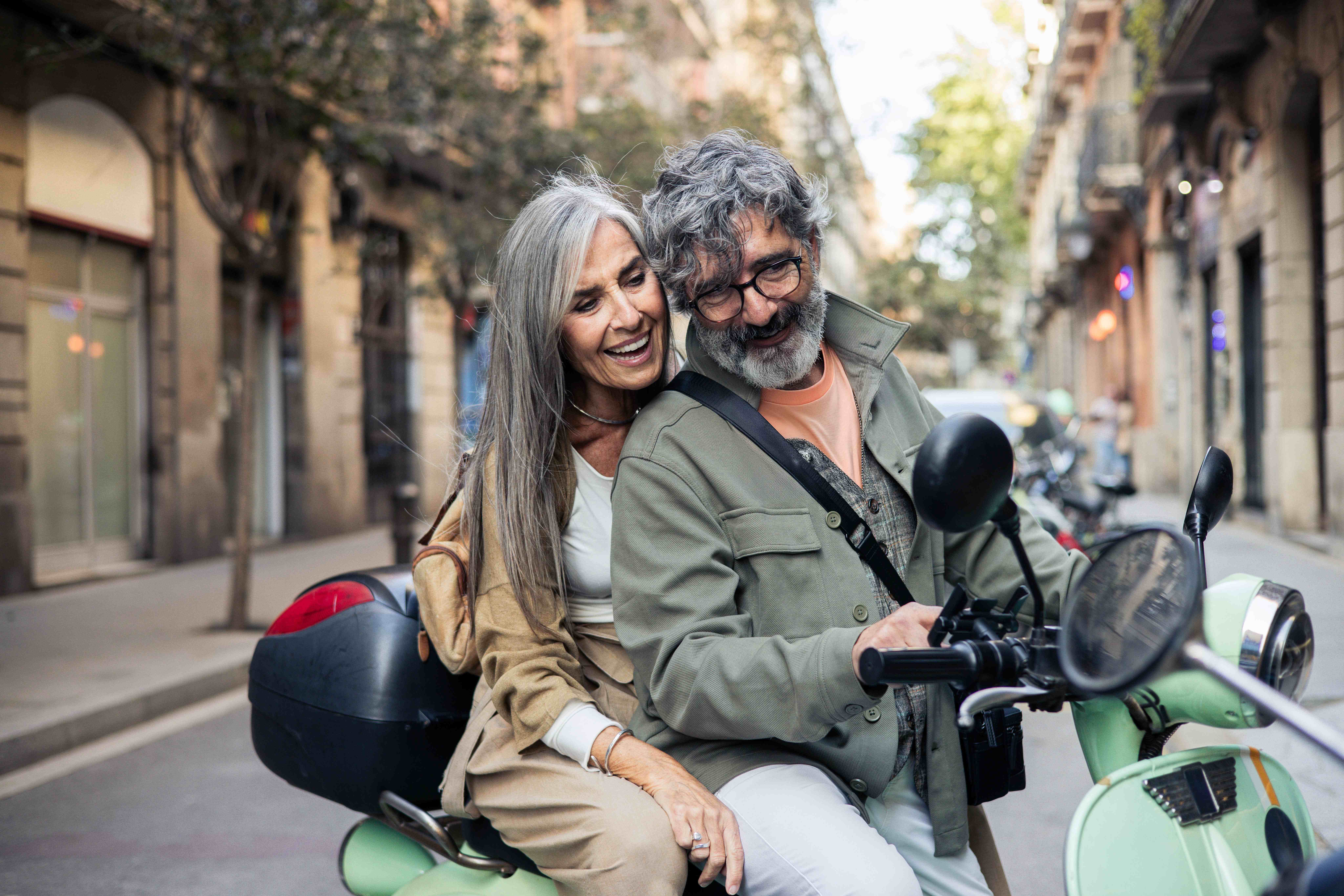 Grandfather, father and daughter sitting in a field laughing