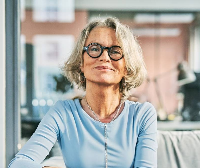 A lady sits on a sofa while looking at the camera