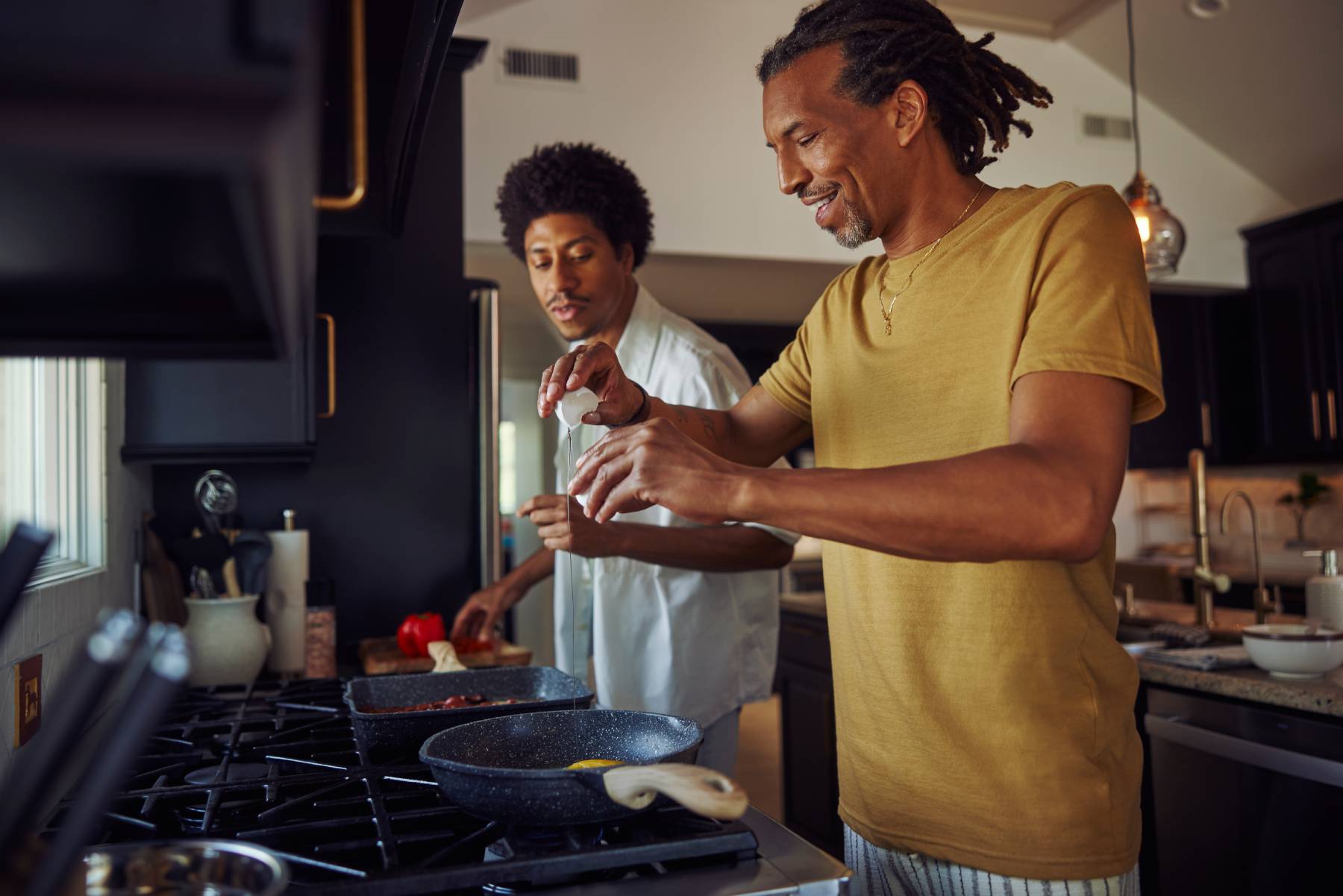 A father and son cook eggs together in the kitchen