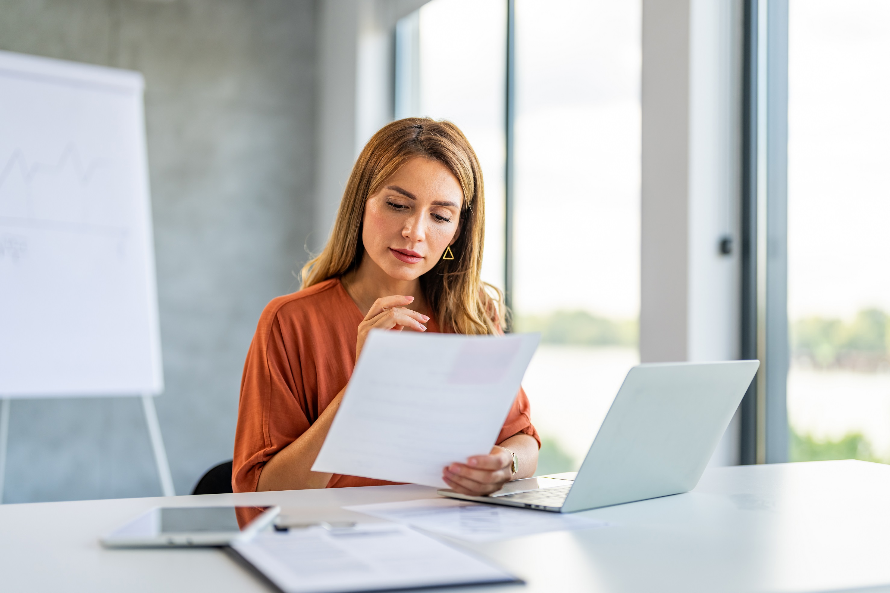 Woman sat at her desk reading a piece of paper