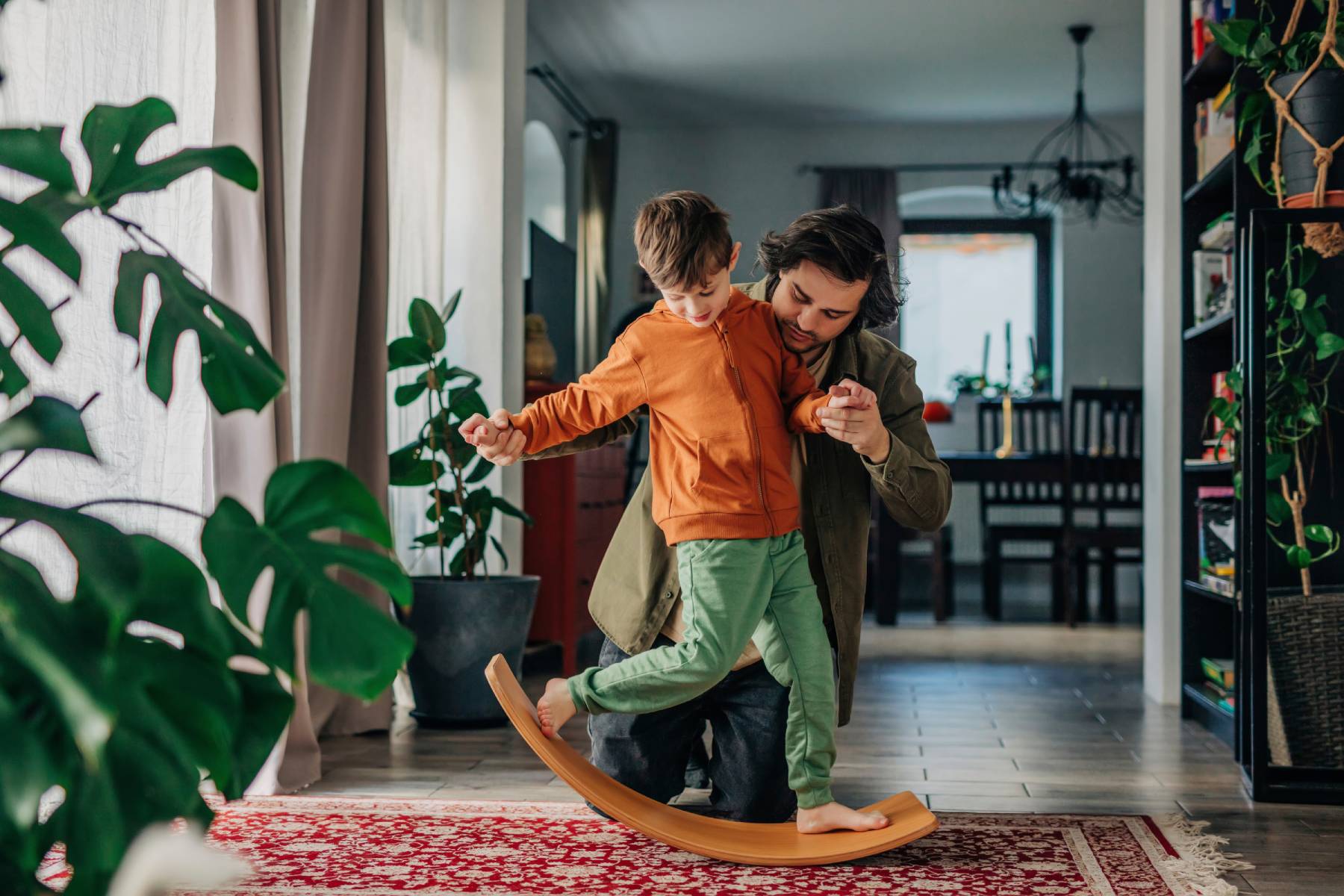 A father and son play together at home on a balance board