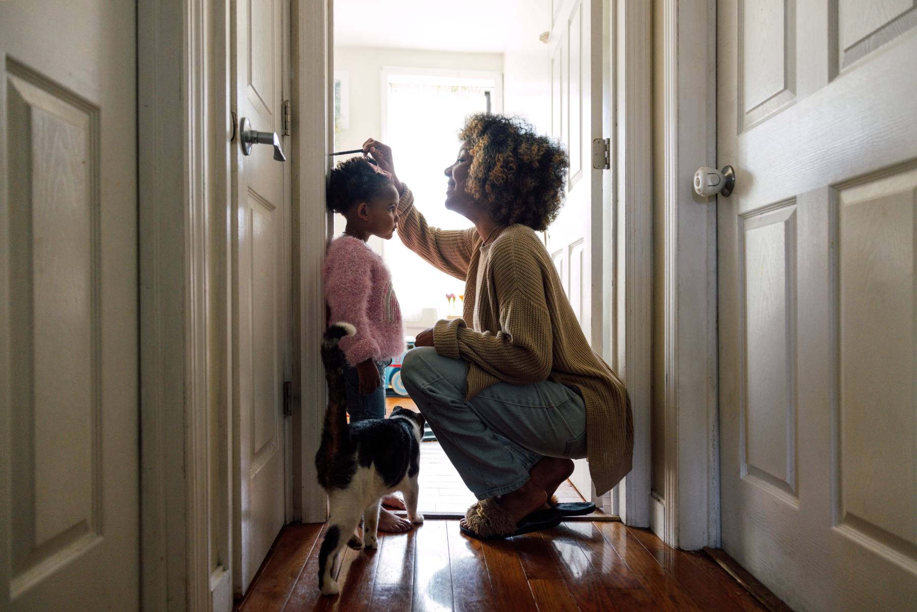 A mother measures the height of her child on a doorway
