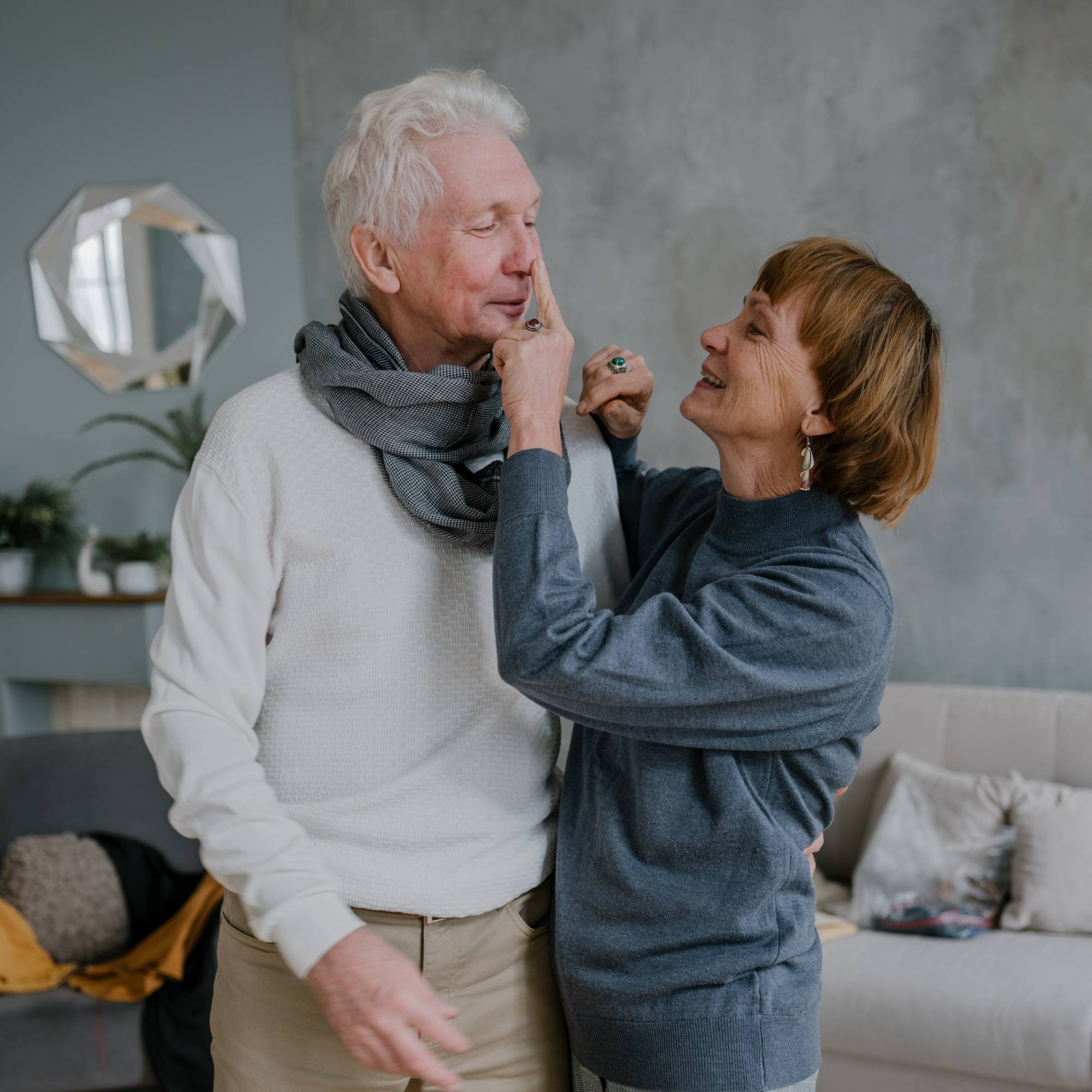 An older couple embrace in their sitting room at home