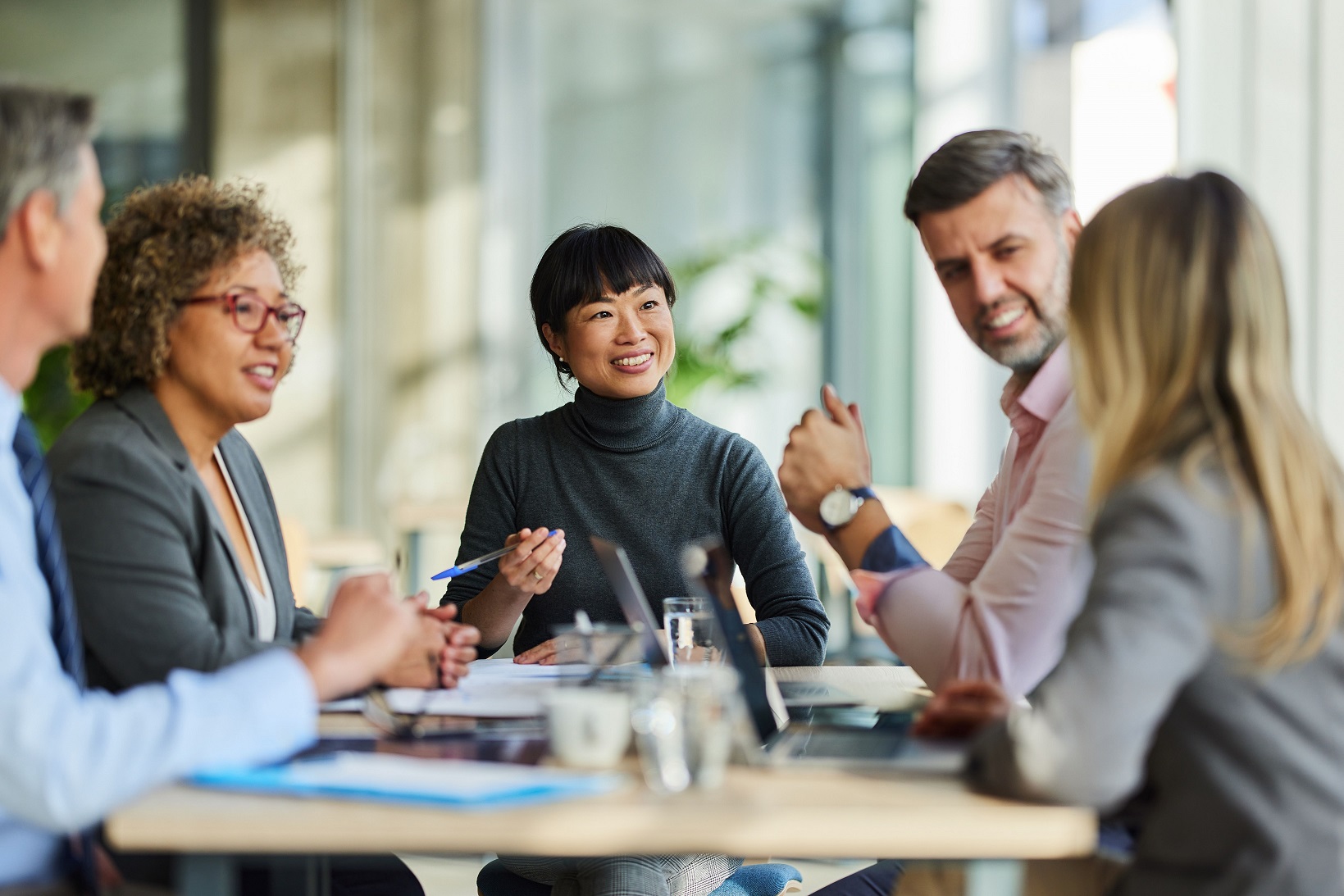 Five charity trustees gathered around a table discussing charity investment topics