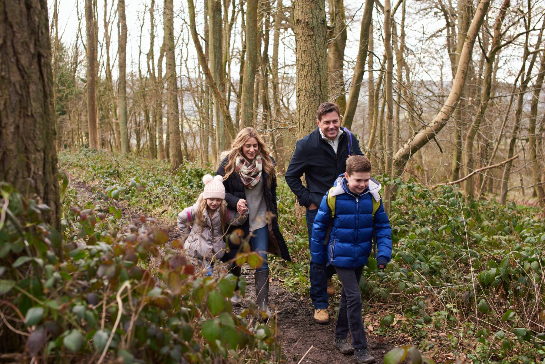 A family of four walking together through a wood