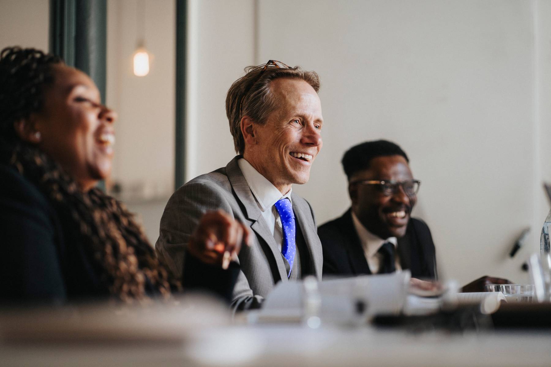 Three colleagues laugh during a meeting