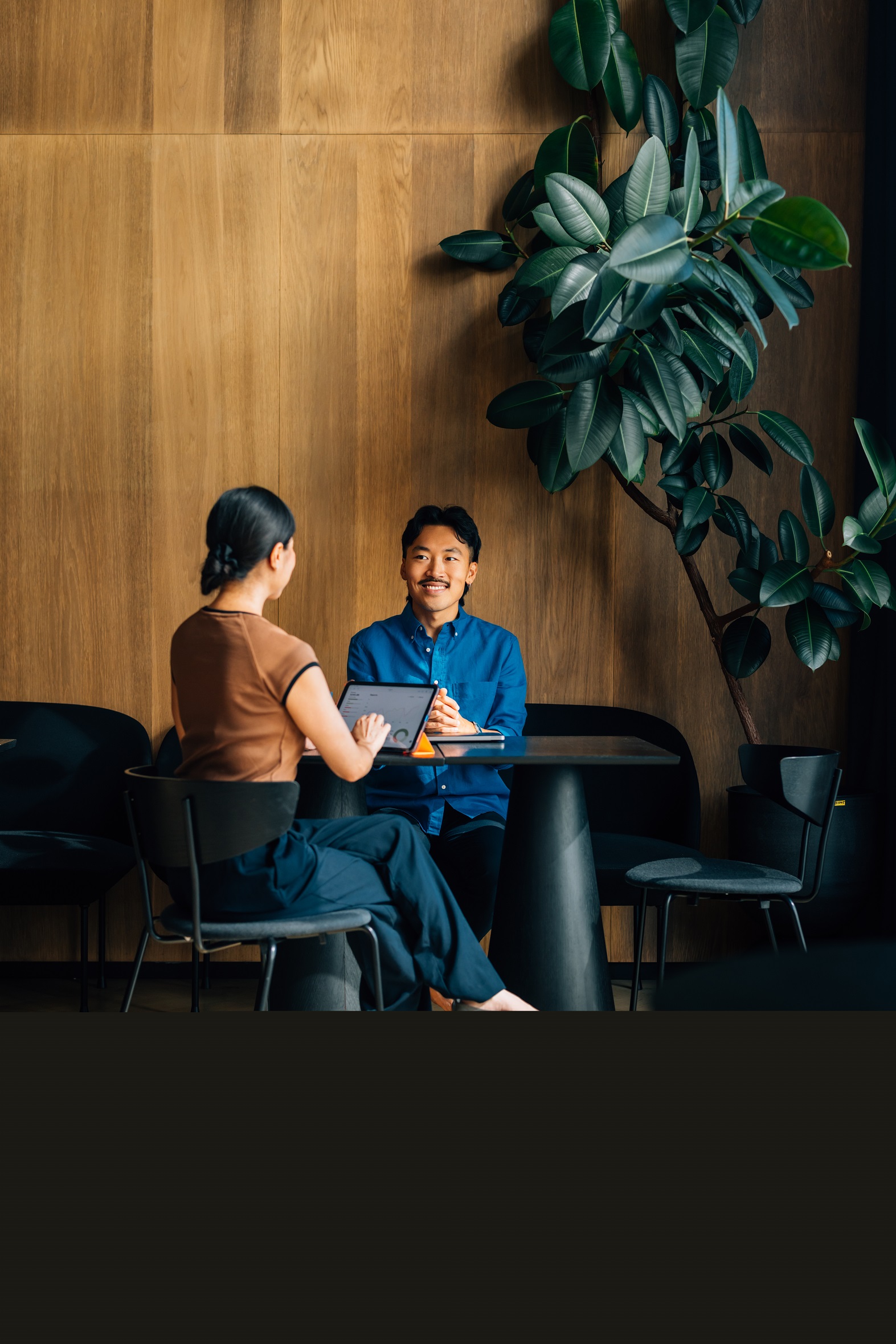 Two people talking at a table with an ipad