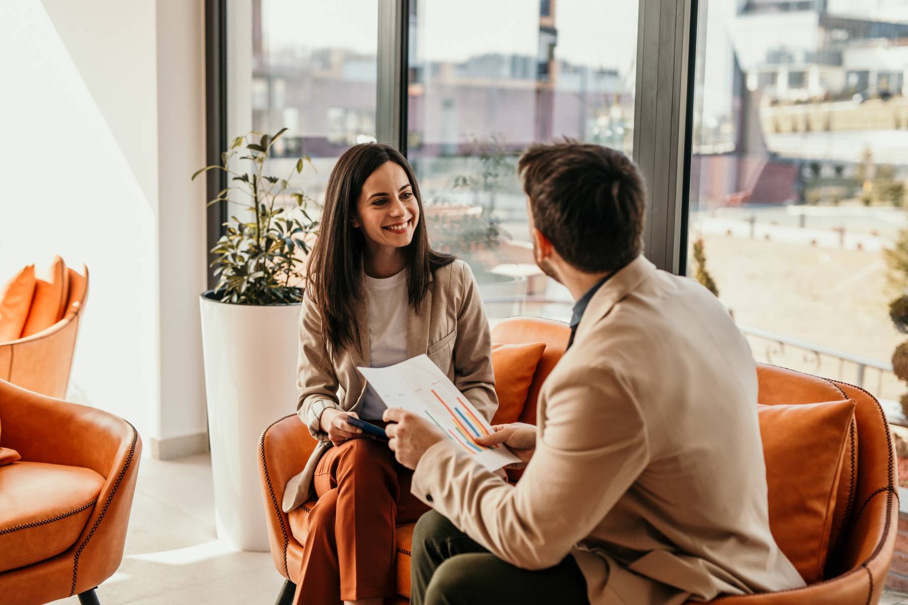 A financial adviser meets with their client on a sofa ijn a light-filled office