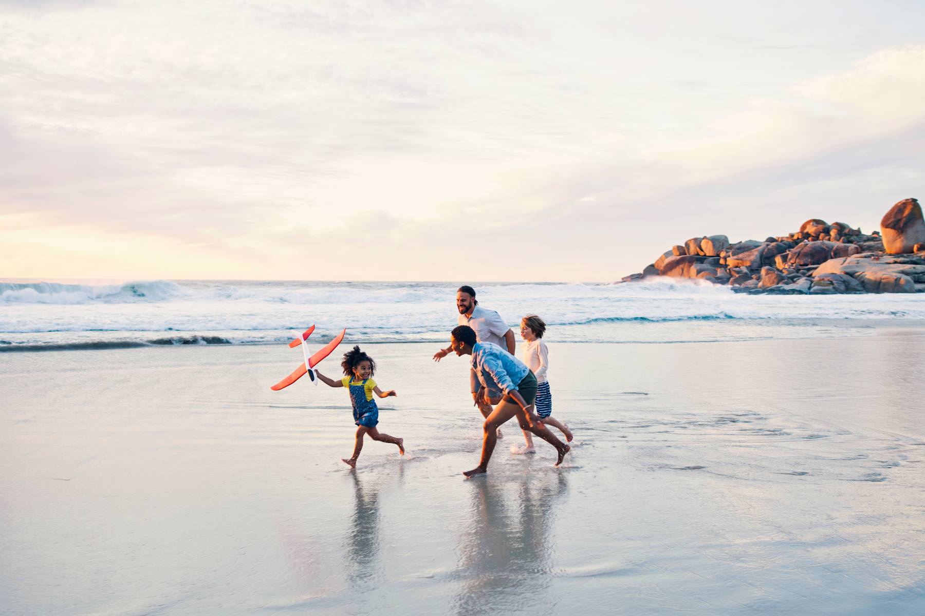 A family play together in the wash of the sea on a beach