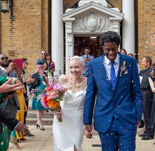 A young couple just married, leaving the registry office as family and friends throw confetti