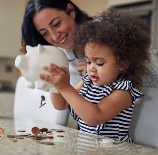 A child emptying her piggy bank as her mother watches