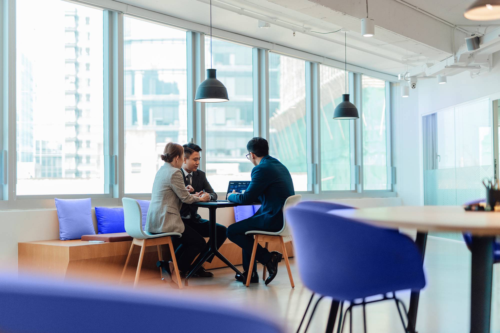 Three colleagues meet in a corporate meeting area to look at statistics on a laptop