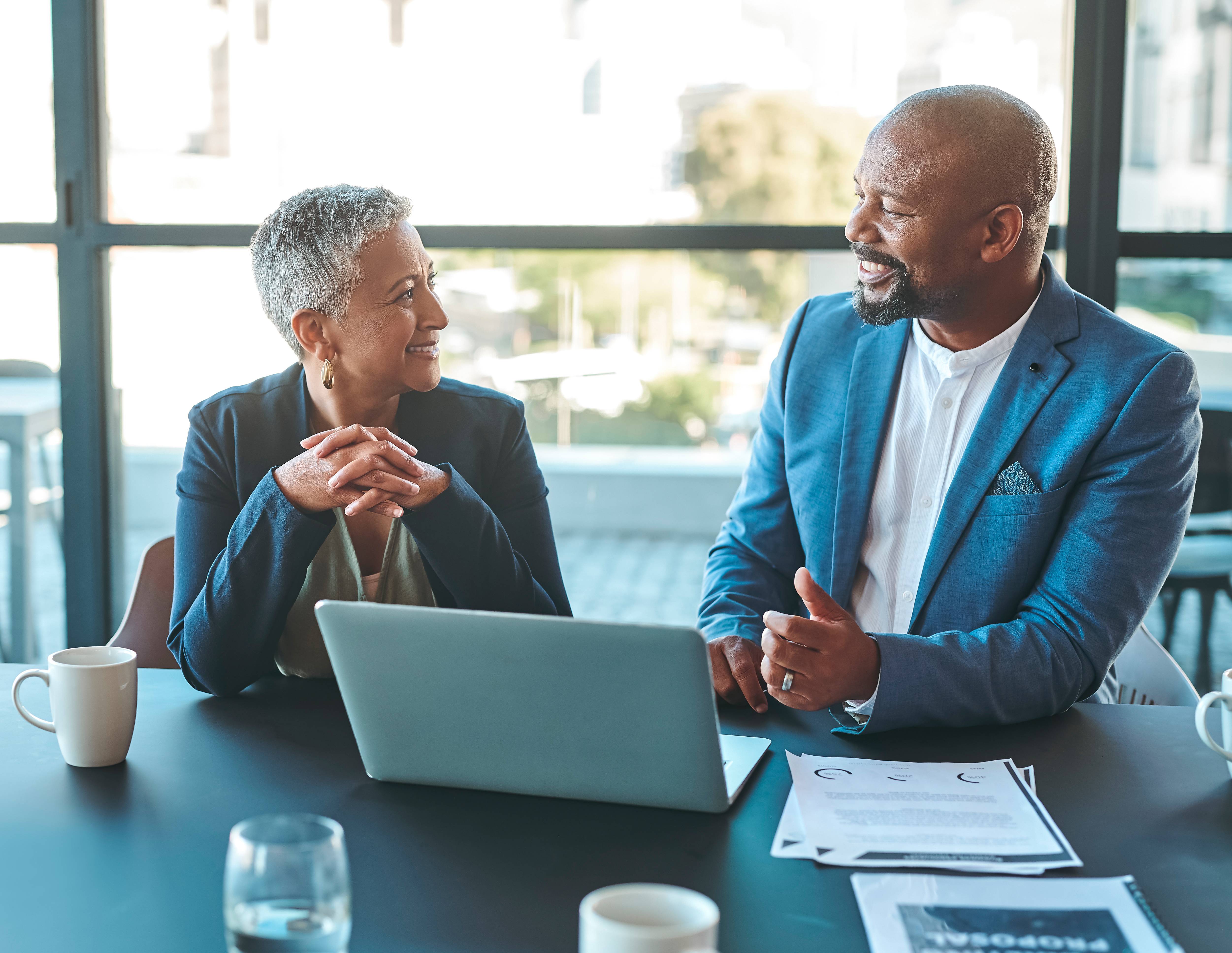 Man and woman sitting and talking in front of a laptop