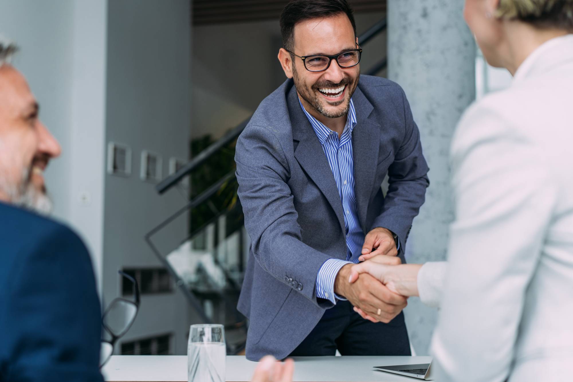 A smiling financial adviser shakes hands with a woman during a meeting