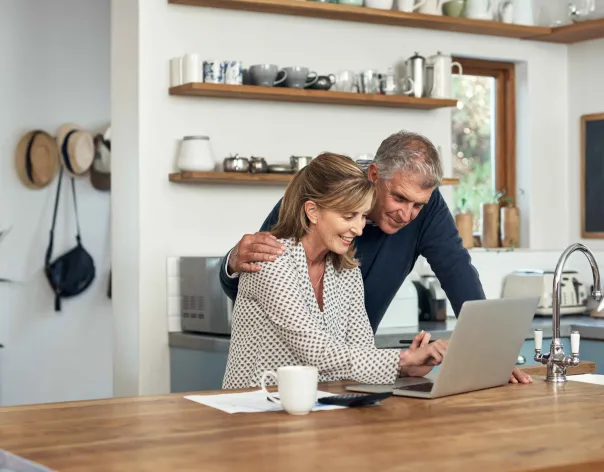 Couple looking excited at their laptop in the kitchen
