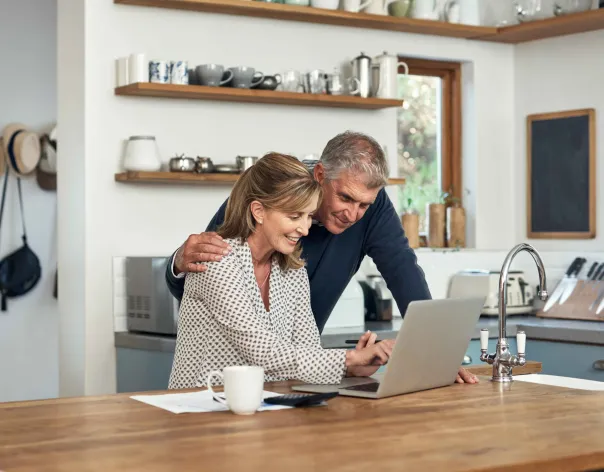 A couple looking excitedly at their laptop in the kitchen