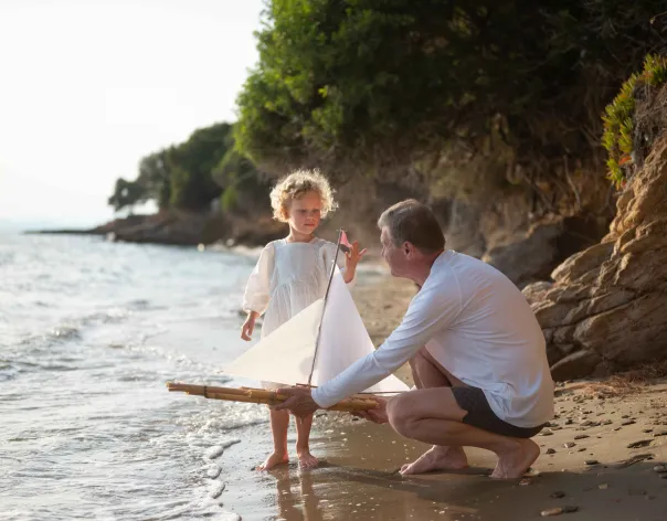Father and daughter setting off a boat on the beach