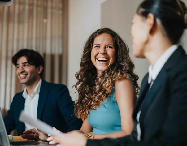 Three colleagues laugh together while in a meeting