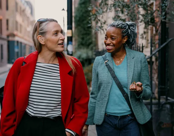 Two women walking and talking down a city street