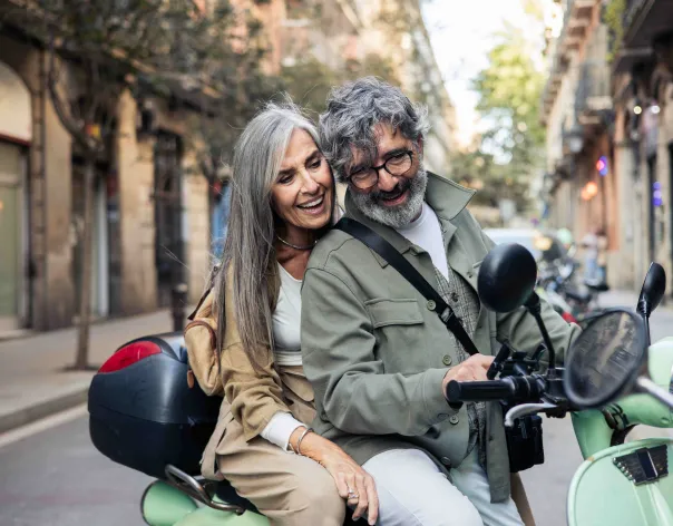 Man and woman laughing on a moped