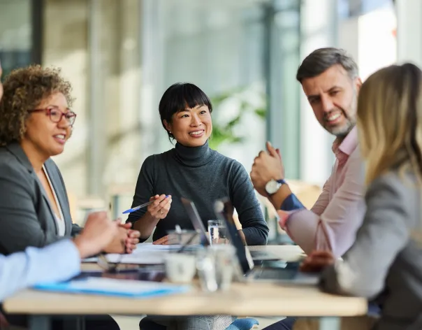 Five charity trustees gathered around a table discussing charity investment topics