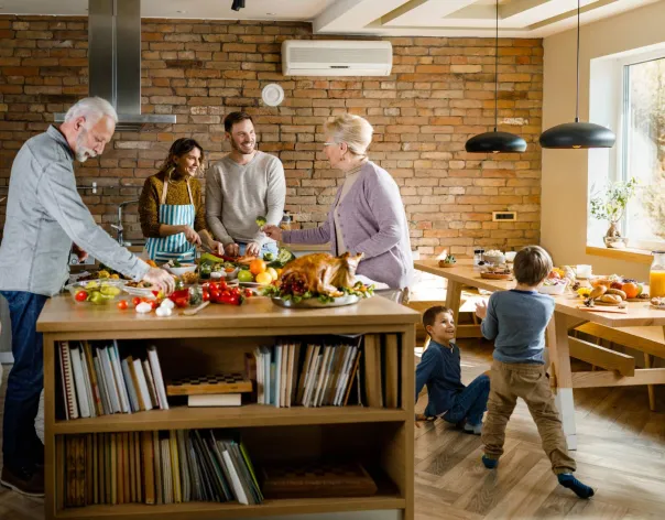 A family featuring three generations gather in a house to have a meal together