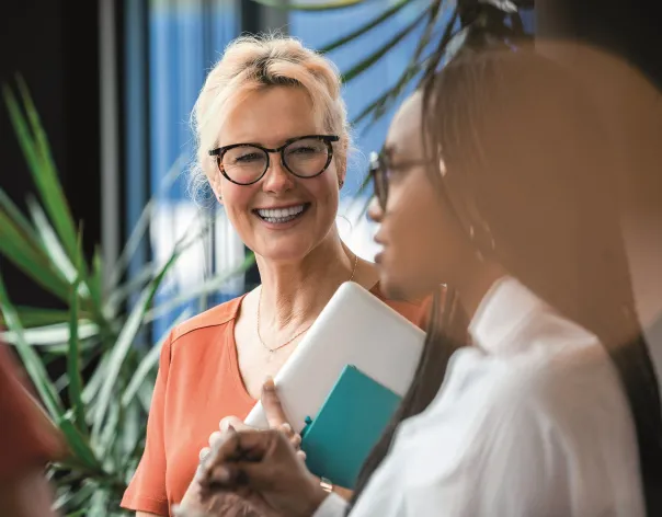 Two female colleagues discussing a topic together at work