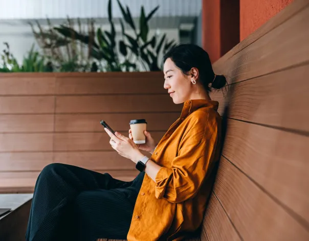 An accountant sits at a cafe to have coffee while checking her investments on her phone