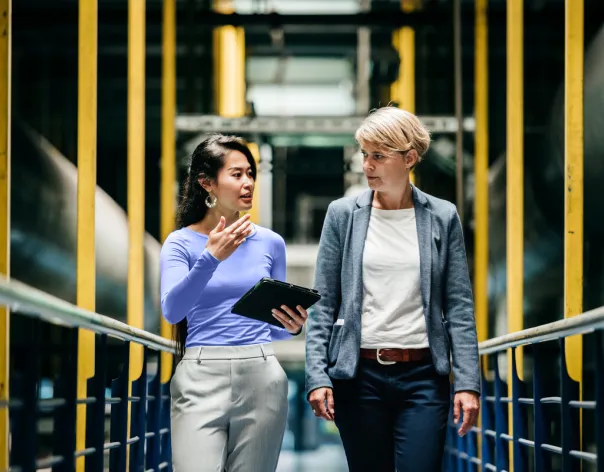 Two business owners walk along the factory floor of their business while discussing their business relief