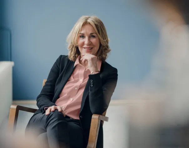 A women in a business suit smiles at the camera while say in an office setting