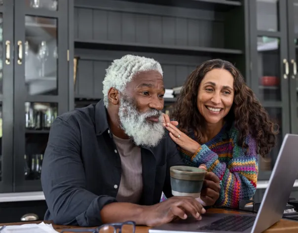 A man and woman speaking to someone via the laptop