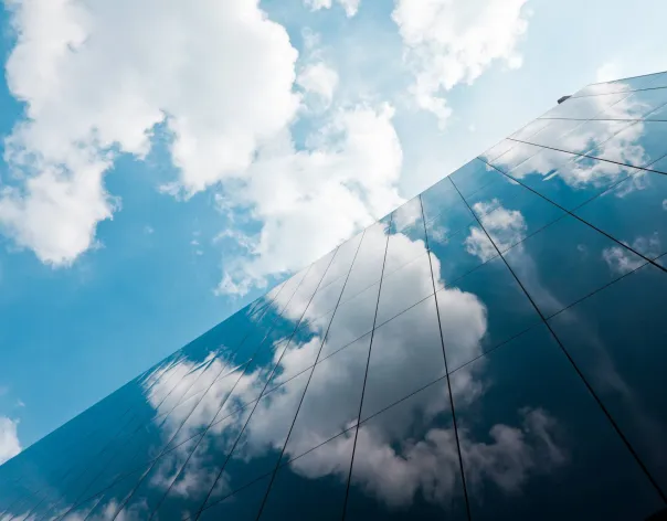Clouds and blue sky reflected in the glass exterior of a corporate office