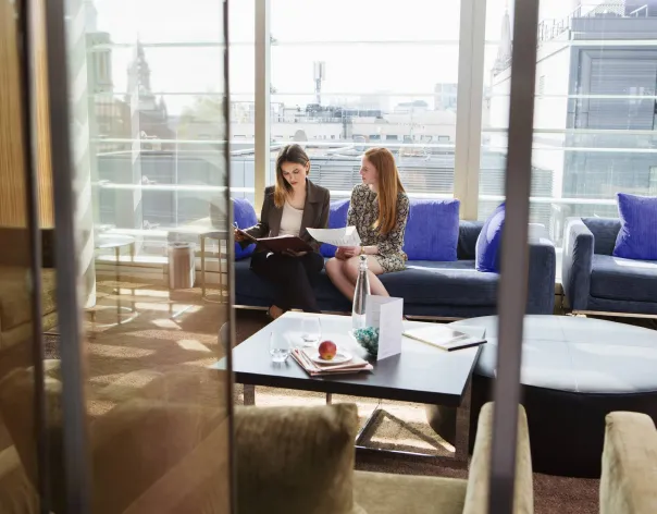 Two Rathbones investment managers sit on an office sofa together and discuss documents