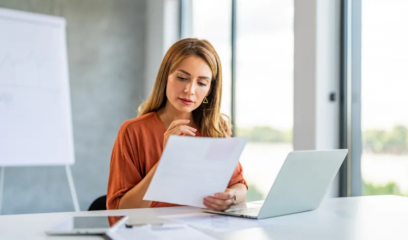 Woman sat at her desk reading a piece of paper