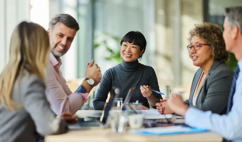 A couple sit together on a grey sofa while looking at a tablet