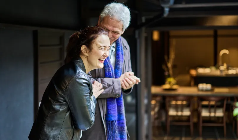 A father and daughter laugh together while standing outside a restaurant