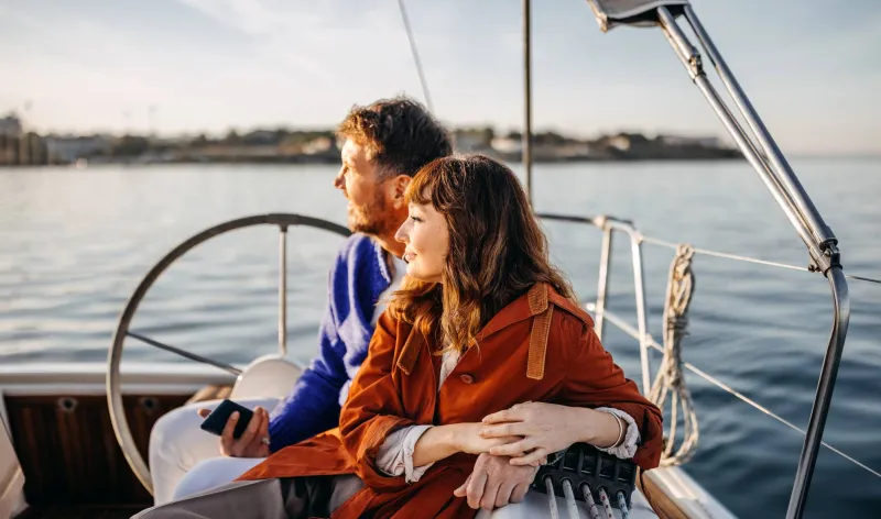 A couple relax on their yacht and look towards the horizon
