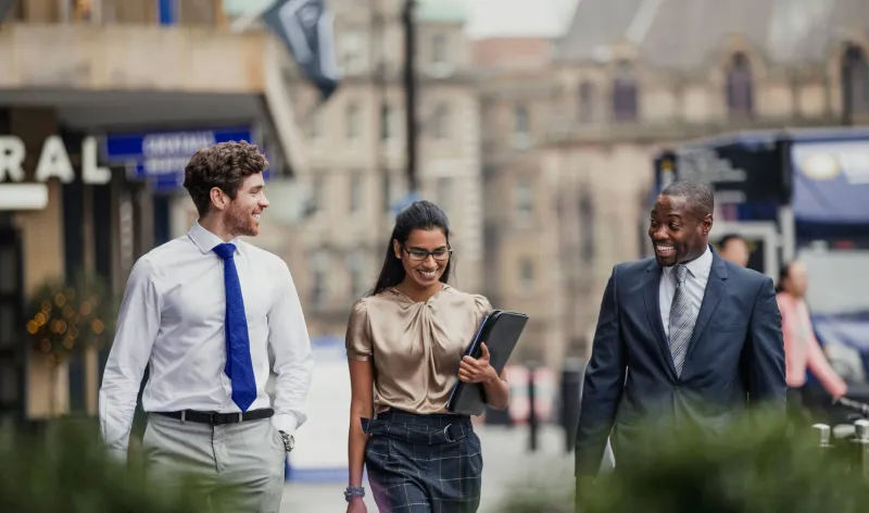 Three colleagues walk and talk through a town together