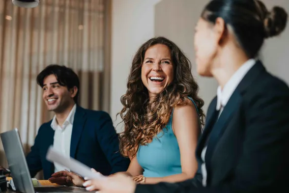 A group of professionals laugh while working together on a project