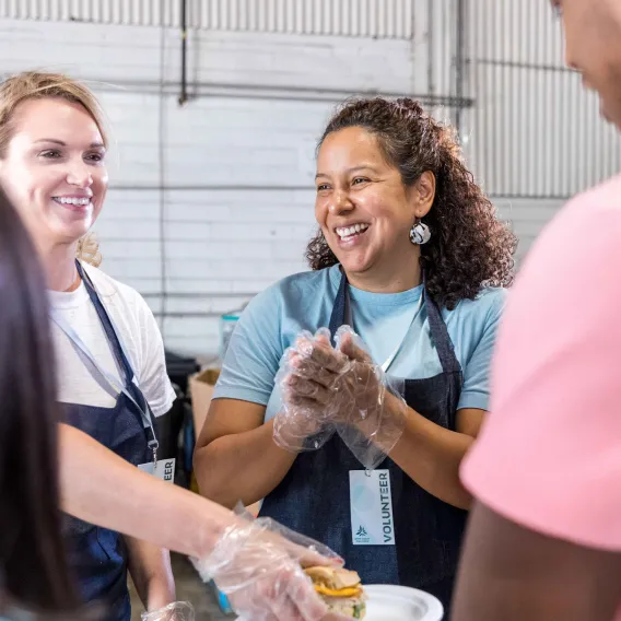 2 voluneets helping feed animals at a farm