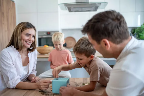 Two parents watch their two sons push coins through a toy