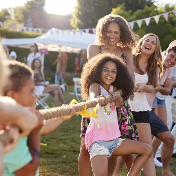 A charity trustee playing tug of war with their family at an outside event