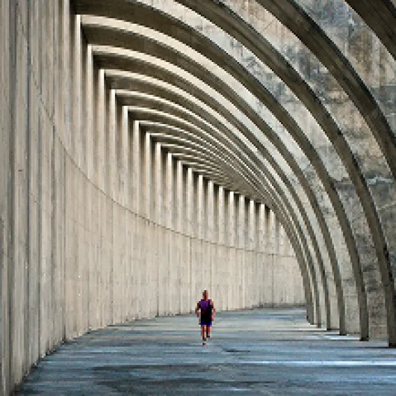 A view of someone running under a large concrete walkway
