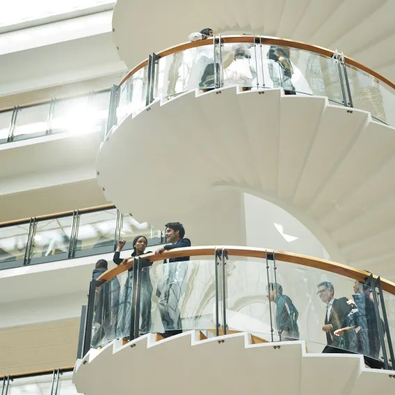 People stand on a spiral staircase looking outwards in a large building