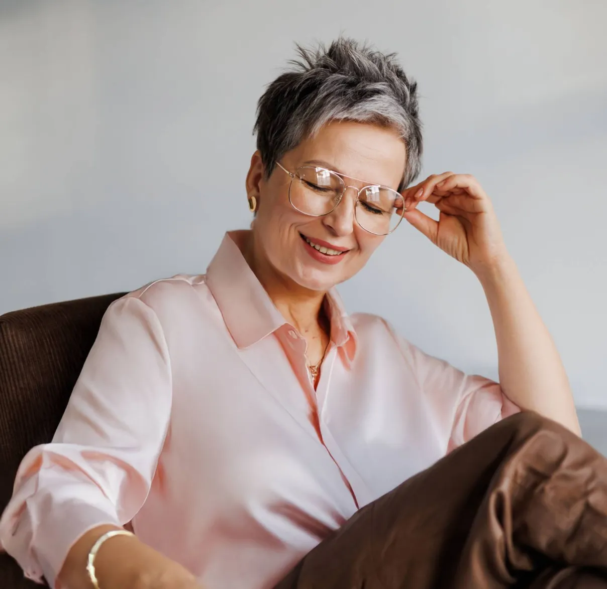 A lady in a pink shirt takes a moment to relax while sitting in an armchair